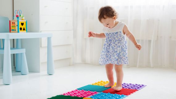 A child walking on a play mat.